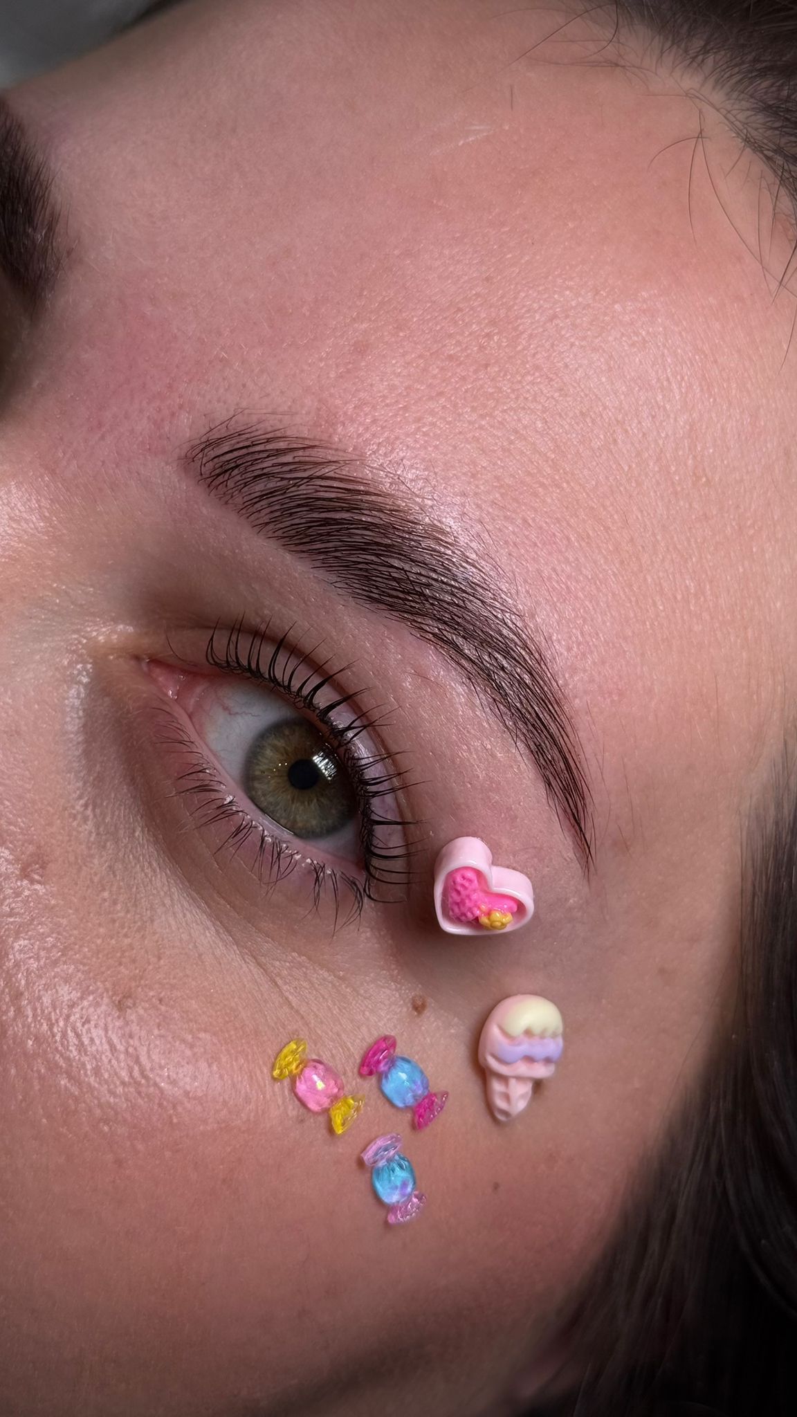 Verzorgde wenkbrauwen in close-up, met kleine snoepjesstickers op de wang